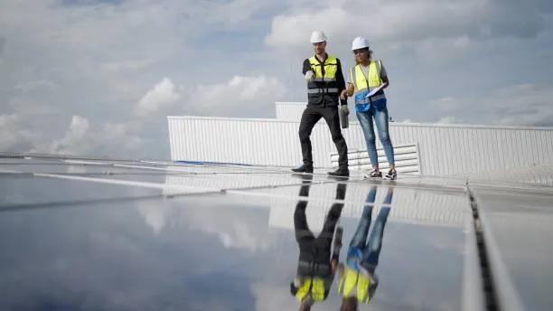 ¿Qué es el factor de potencia? Dos personas inspeccionando paneles solares para verificar su eficiencia energética y el factor de potencia.