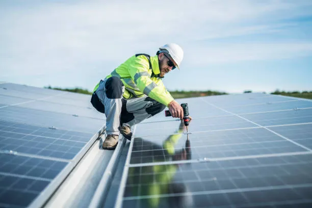 Profesional revisando instalaciones eléctricas junto a paneles solares en empresas para tareas de mantenimiento especializado.