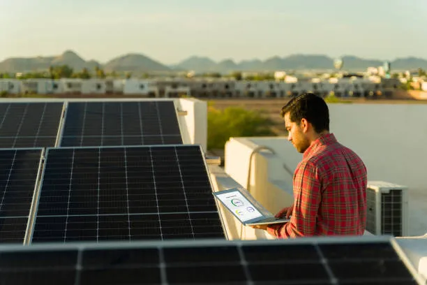 Hombre con computadora portátil al lado de un sistema solar, representando las tendencias en energía solar en México para 2025
