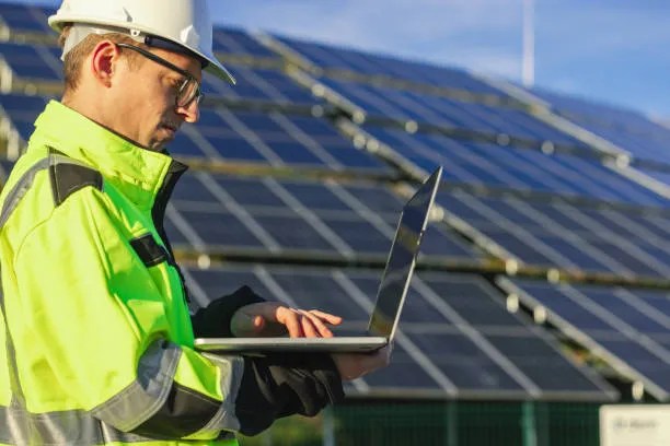 Persona trabajando con computadora portátil frente a sistema con varios tipos de inversores solares instalados