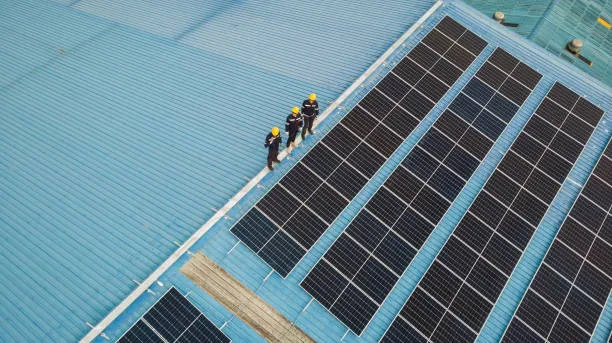 Especialistas evaluando el rendimiento y conexiones de módulos instalados en el techo de una empresa, optimizando la producción energética con paneles solares en Irapuato