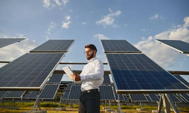 Técnico observando un sistema de paneles solares alineados desde su tablet, ilustrando con claridad cómo sé cuánta energía están generando mis paneles solares en una instalación empresarial.
