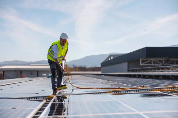 Vista de un técnico realizando mantenimiento preventivo y enseñando cada cuánto tiempo debo limpiar los paneles solares según el clima.