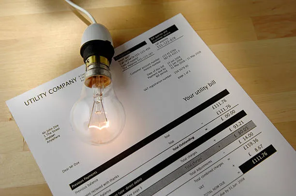 Recibo de luz junto a un foco encendido representando el análisis del consumo eléctrico y la razón detrás de los cambios mínimos en el ahorro ¿Por qué mi recibo no bajó tanto como esperaba con mis paneles solares?
