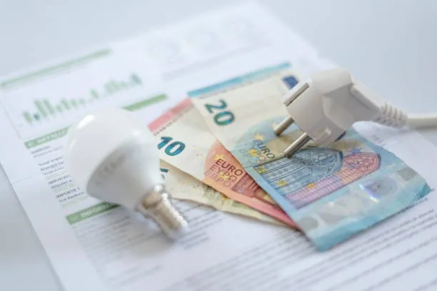 Recibo eléctrico colocado junto a un foco brillante simbolizando el comportamiento del consumo energético y sus variaciones ¿Por qué mi recibo no bajó tanto como esperaba con mis paneles solares?