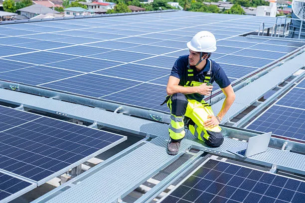 Técnico especialista realizando una inspección y diagnóstico del cableado y las conexiones del inversor en un tejado industrial, confirmando el cumplimiento de la cobertura al preguntarse ¿Qué tipo de garantía tienen mis paneles solares y el inversor? por parte del fabricante.