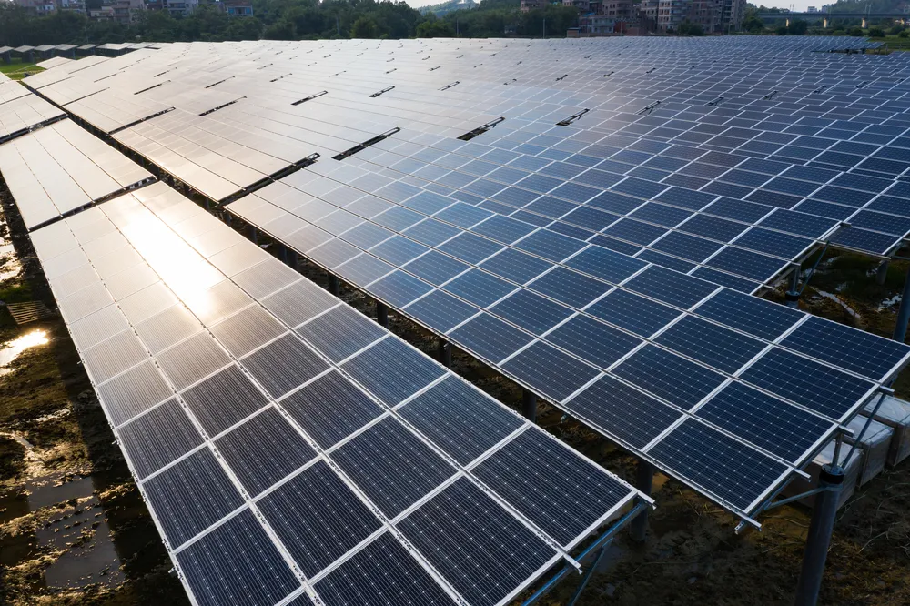 Un vasto campo de paneles solares captura la luz, ilustrando la escala de la producción de energía solar y los posibles ahorros tanto si se elige rentar vs comprar paneles solares.