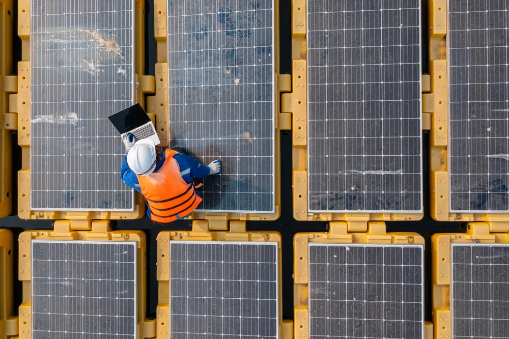 La ingeniería detrás de la instalación de paneles solares flotantes es compleja, con un técnico especializado verificando el rendimiento y la producción de energía del innovador sistema.