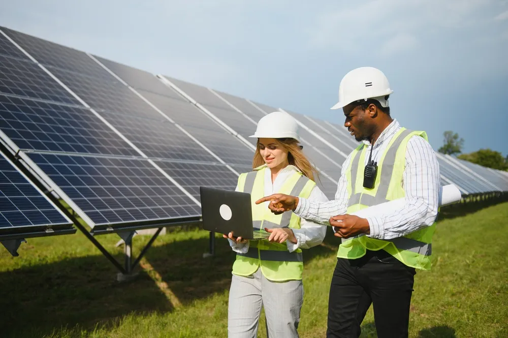 Ingenieros revisando datos técnicos en una laptop para maximizar las ventajas de la energía solar en campo abierto
