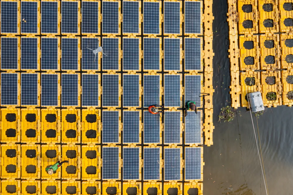 Vista aérea de un complejo industrial y casas con paneles solares instalados en sus techos bajo la luz del día clara.