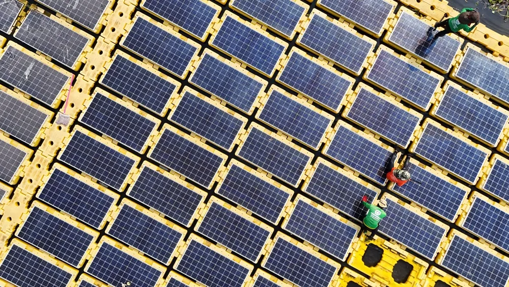 Perspectiva cenital de una cuadrilla trabajando en el mantenimiento de una planta solar flotante sobre una laguna.
