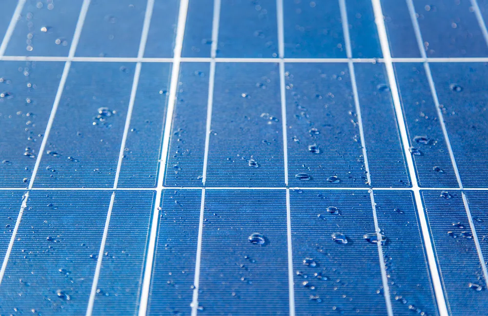 Textura de panel solar azul con pequeñas gotas de agua esparcidas por la superficie después de una lluvia ligera.