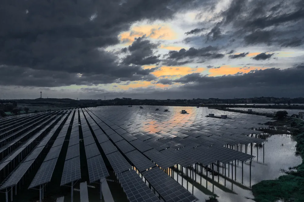 Paisaje de un parque solar extenso con paneles instalados sobre agua bajo nubes oscuras de lluvia inminente.