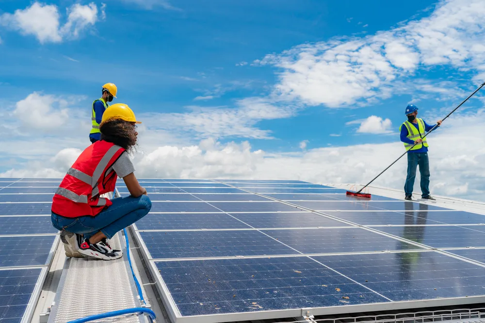 Cuadrilla de técnicos especializados ejecutando tareas de mantenimiento preventivo de paneles solares en techos amplios.