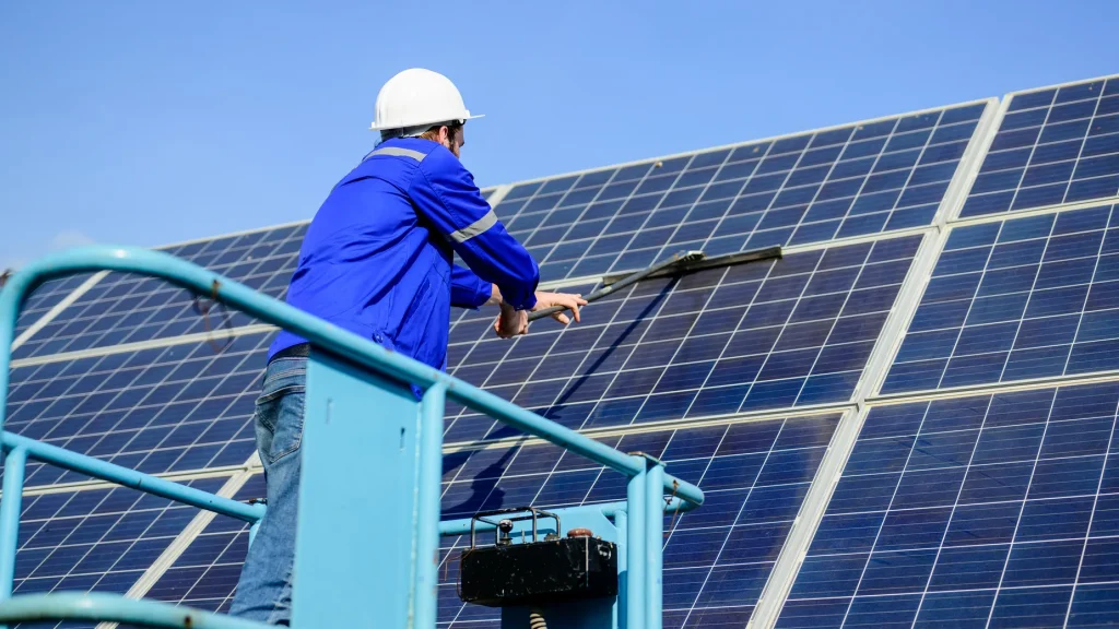 Cuánto cuesta un mantenimiento preventivo de paneles solares: Técnico limpiando módulos solares