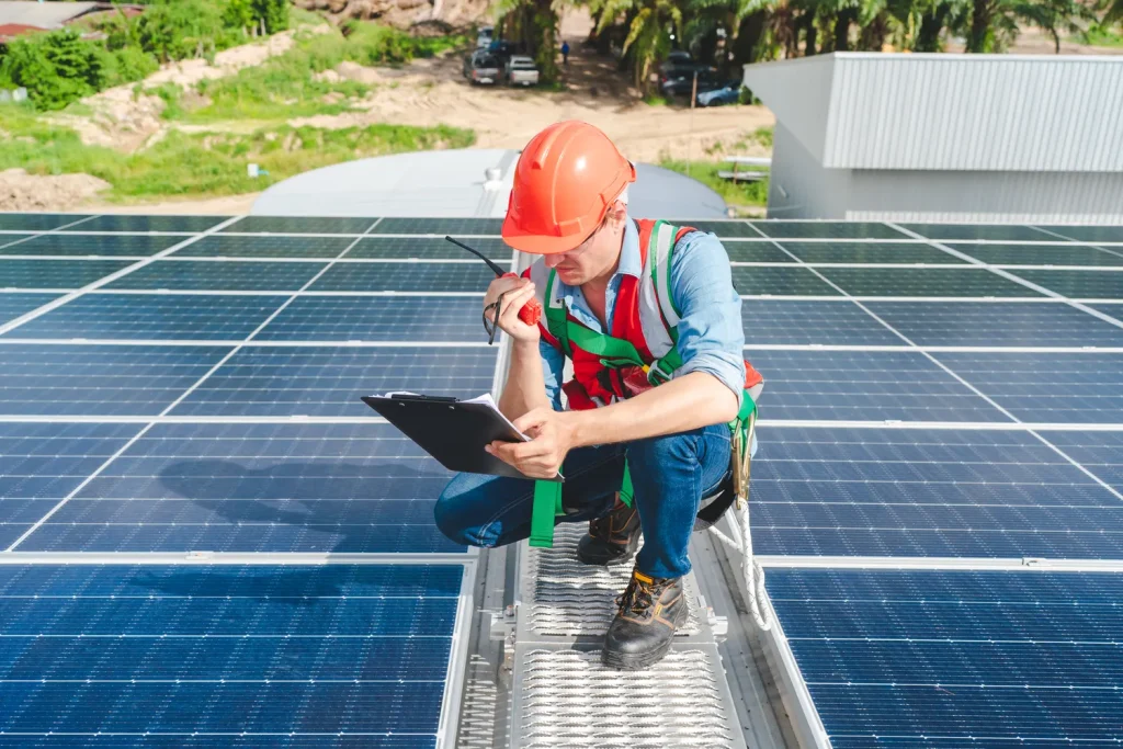 Ingeniero con casco naranja usando un radio para decir cuánto cuesta un mantenimiento correctivo de paneles solares .