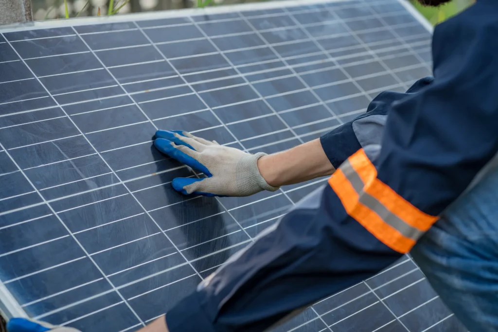 Close up de un ingeniero con guante protector revisando la superficie de un panel solar para decir cuánto cuesta un mantenimiento correctivo de paneles solares .