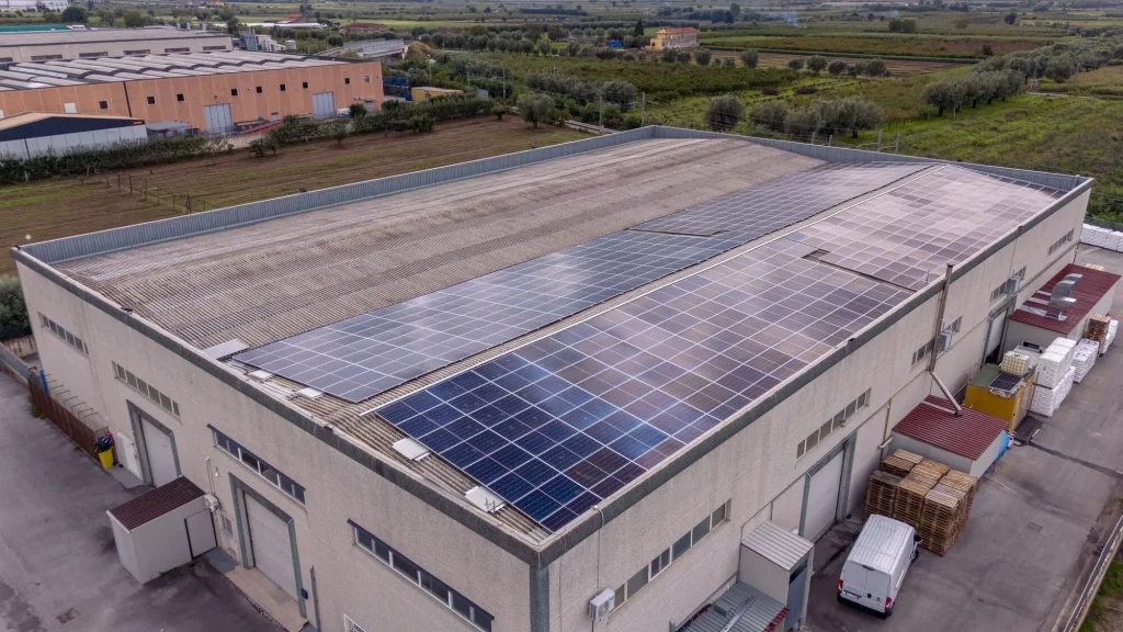 Panorámica de una gran superficie de paneles solares para fábricas y naves industriales instalados en un techo industrial.