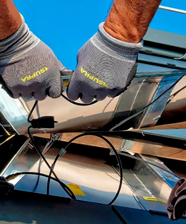Manos de un técnico de una empresa de paneles solares realizando conexiones eléctricas en una instalación de techo.