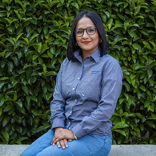 Ana Rodríguez, integrante del equipo de telemarketing de una empresa de paneles solares, sentada frente a un seto natural.