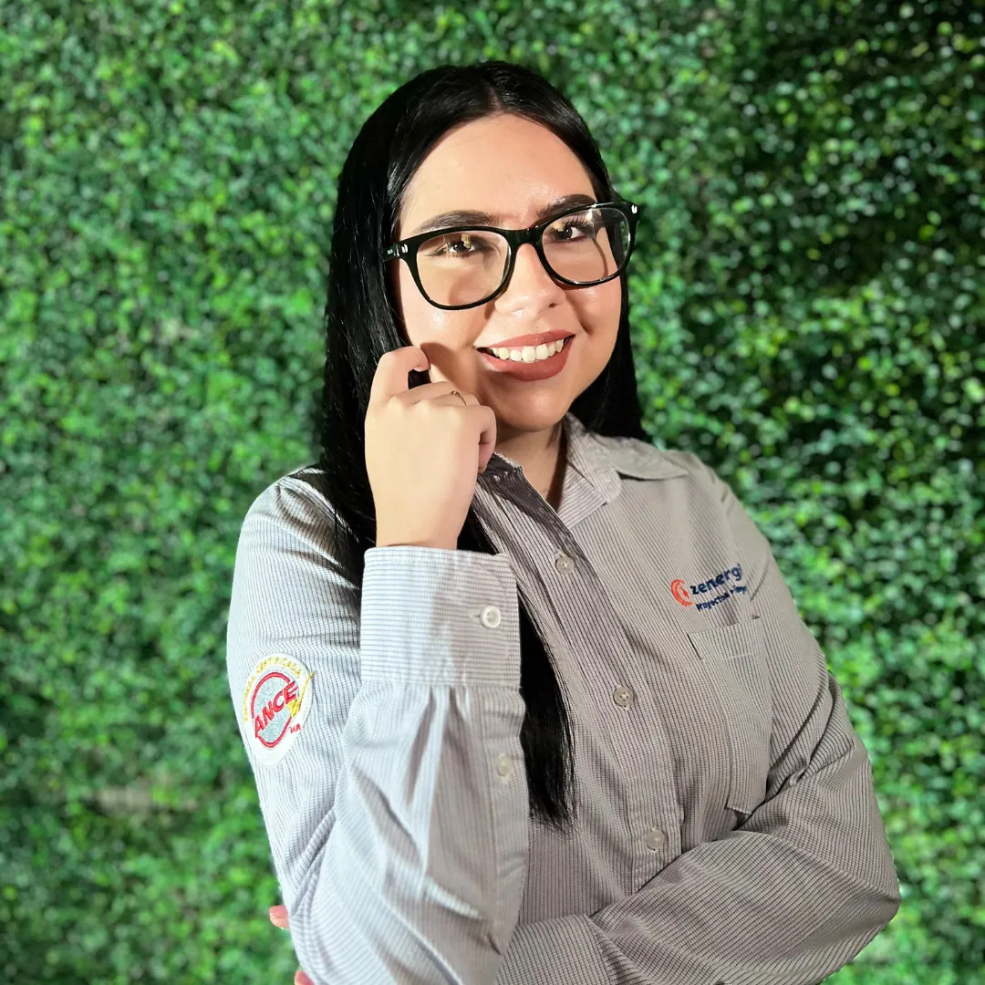 Hannia Rodríguez, de atención al cliente en una empresa de paneles solares, sonriendo con gafas frente a fondo verde.