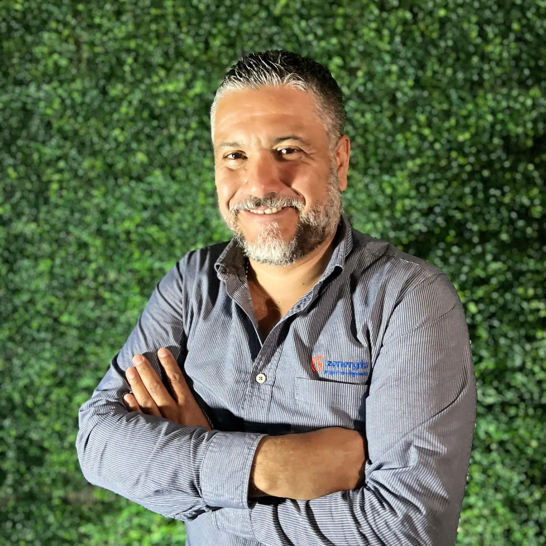 Javier Jarero, consultor especializado de nuestra empresa de paneles solares, sonriendo frente a un fondo de follaje verde.
