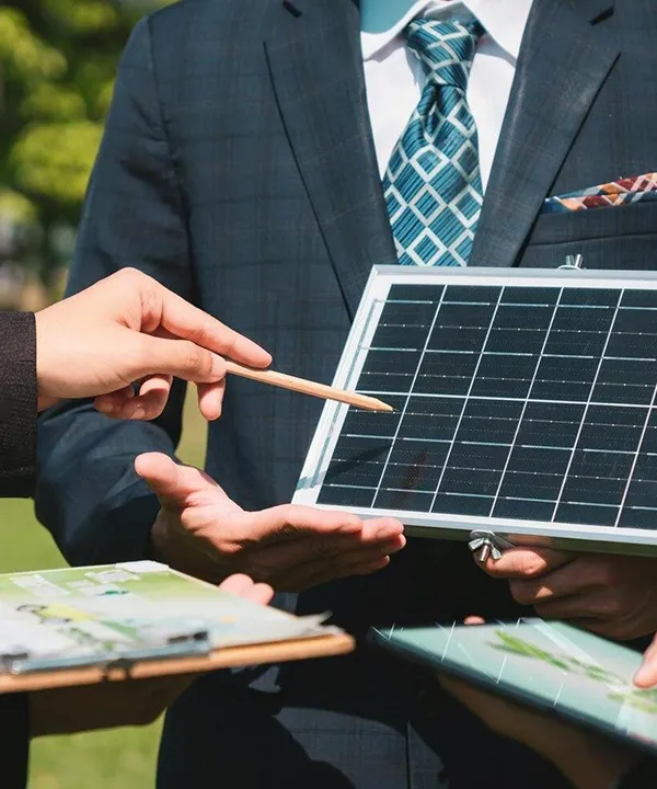Dos personas en el exterior revisando un panel solar y documentación con una tableta.