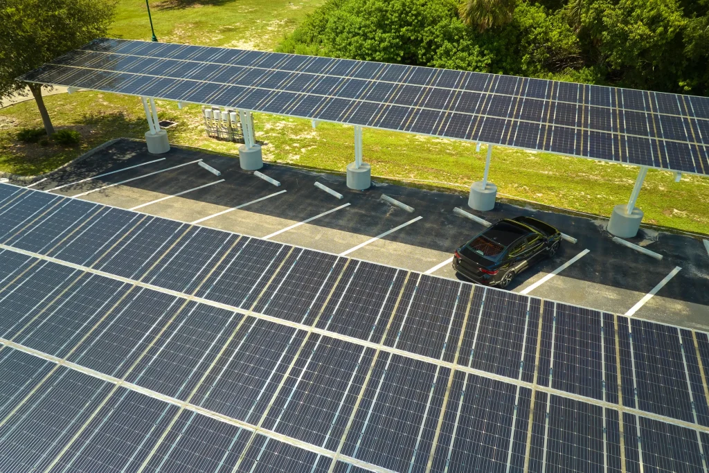 Auto estacionado bajo marquesinas solares y la duda de cuánto tiempo tarda en cargar un panel solar en esta estructura.