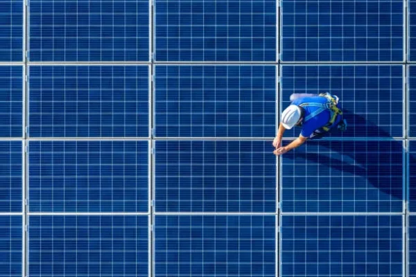 Un hombre instalando paneles solares con células fotovoltaicas, mejorando la eficiencia energética de la vivienda.